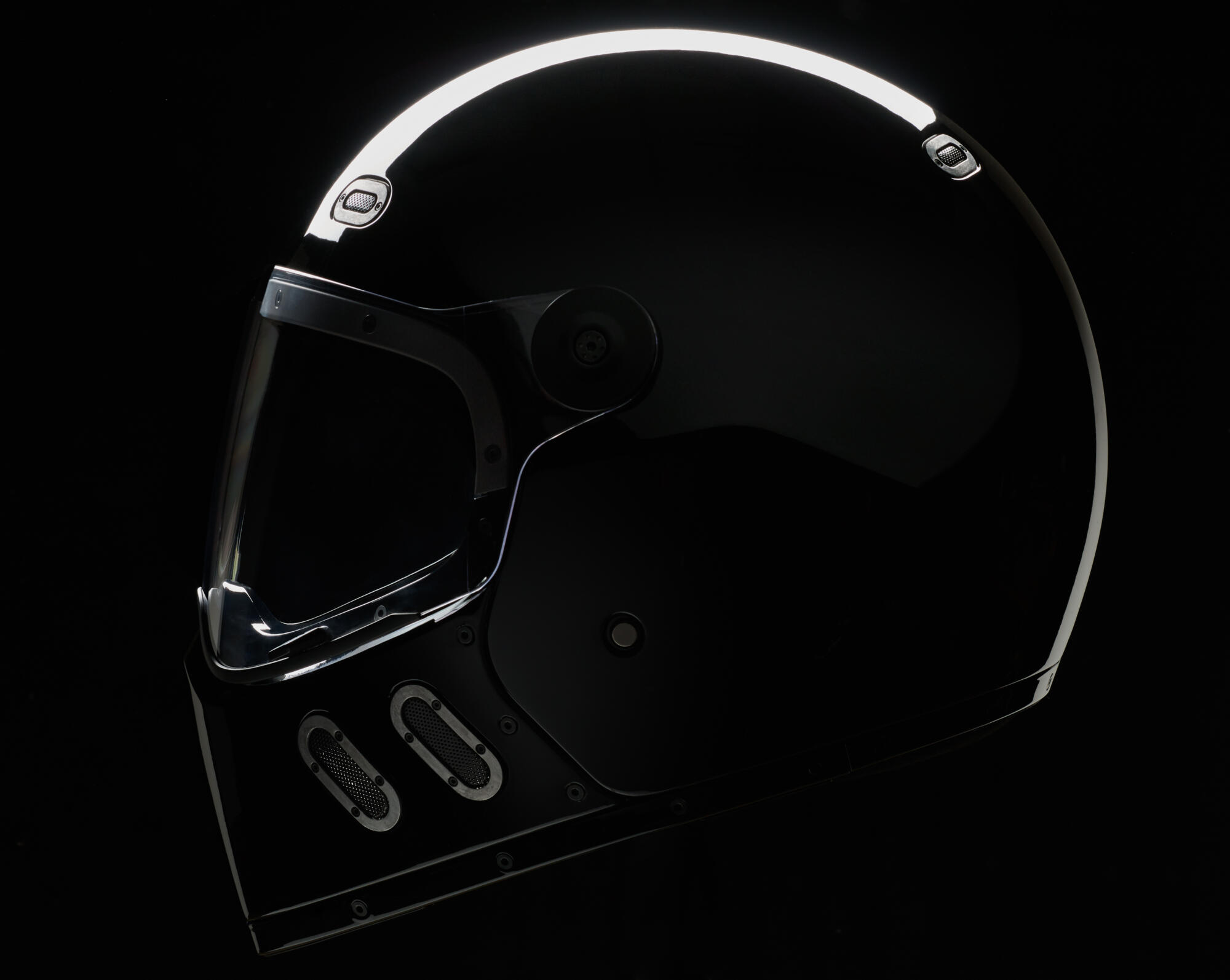 Photographie professionnelle d'un casque de moto noir mat au design moderne et épuré, éclairé dramatiquement sur fond sombre. Image réalisée par Studio ZE, photographe d'objet et d'équipement moto à Toulouse.