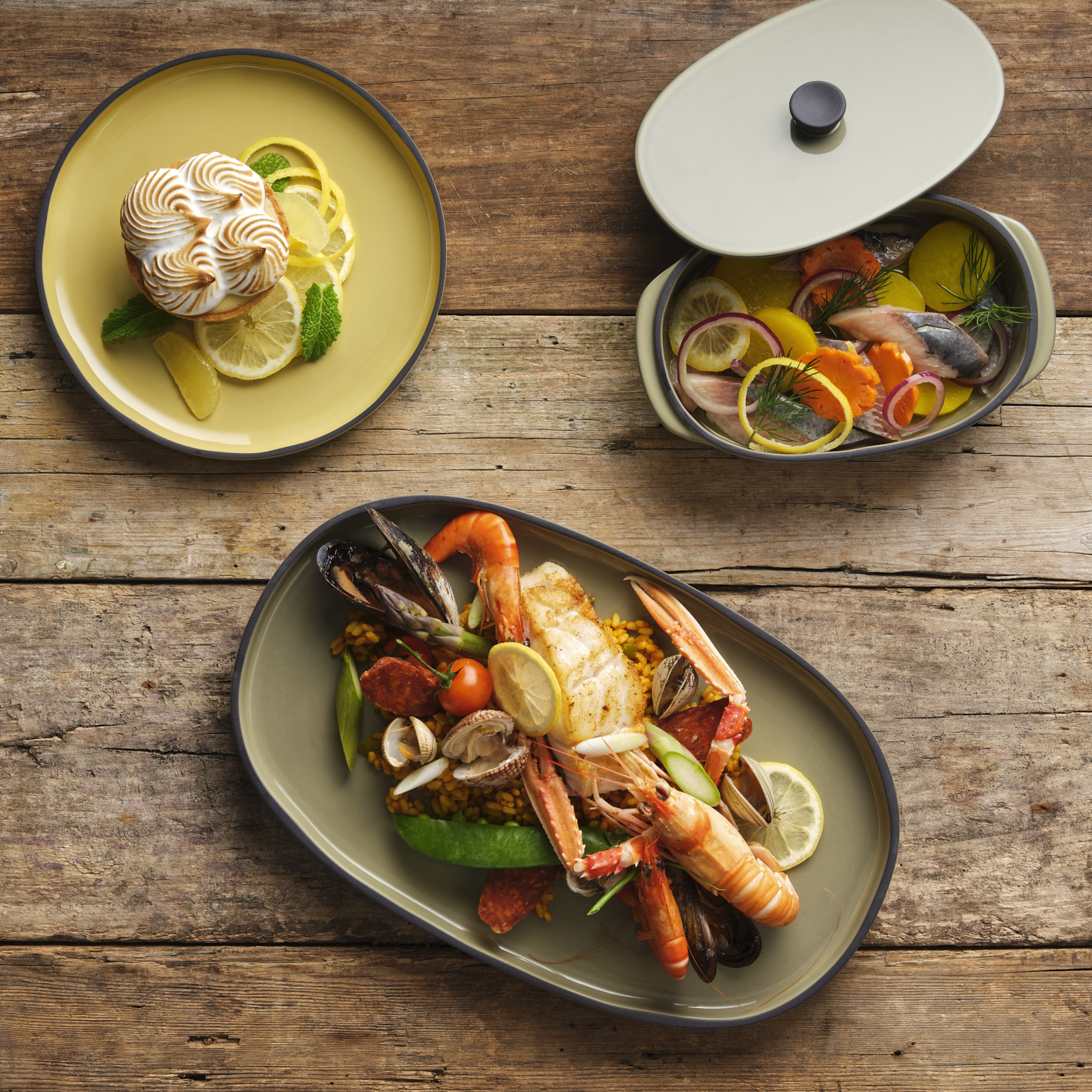 Photographie professionnelle d'un plat de fruits de mer aux langoustines et d'une tartelette au citron meringuée sur une table en bois. Image réalisée par Studio ZE, photographe culinaire de plats à Toulouse.