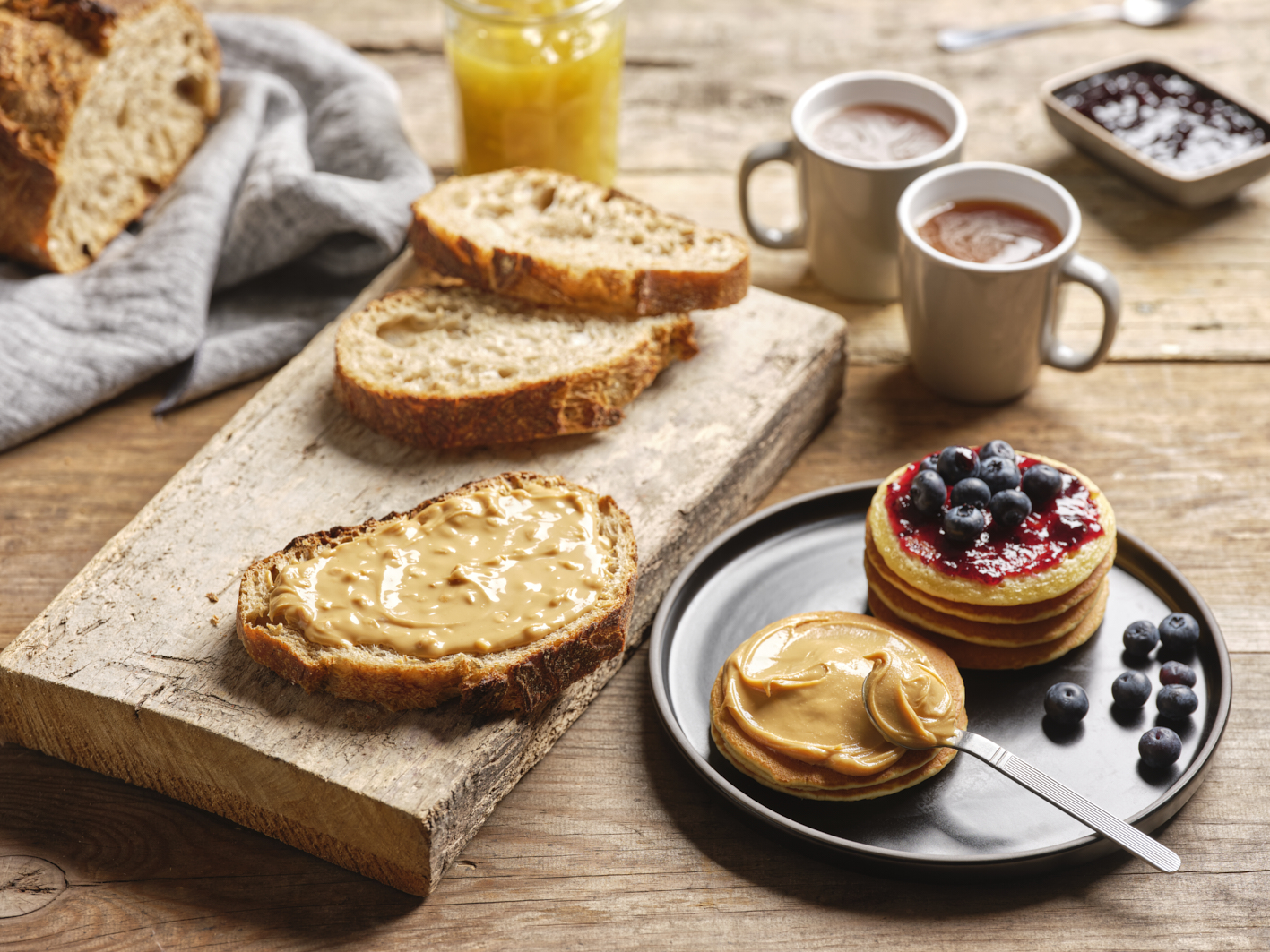 Photographie professionnelle d'une tartine de pain grillé avec du beurre de cacahuète, accompagnée de pancakes et café. Studio ZE, photographe culinaire à Toulouse.