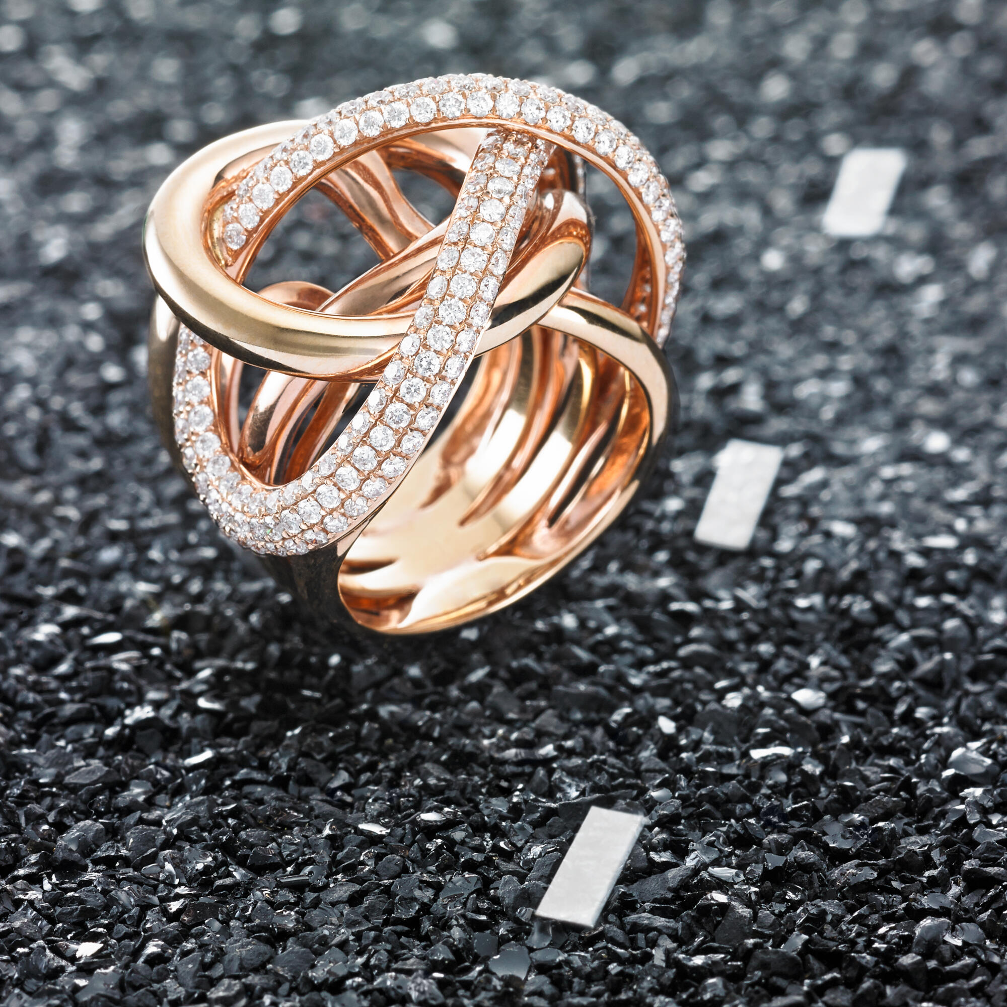 Photographie d'une bague de luxe en or rose avec de nombreux diamants, design entrelacé. Par Studio ZE, photographe bijoux à Toulouse.