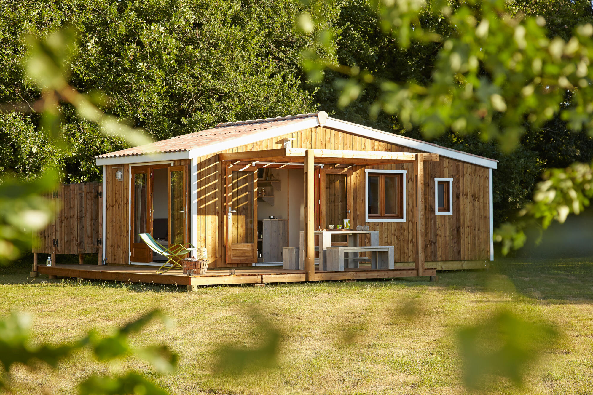 Photographie d'un bungalow en bois avec terrasse en pleine nature, idéal pour hébergement de loisirs. Par Studio ZE, photographe d'architecture et de gîtes à Toulouse.