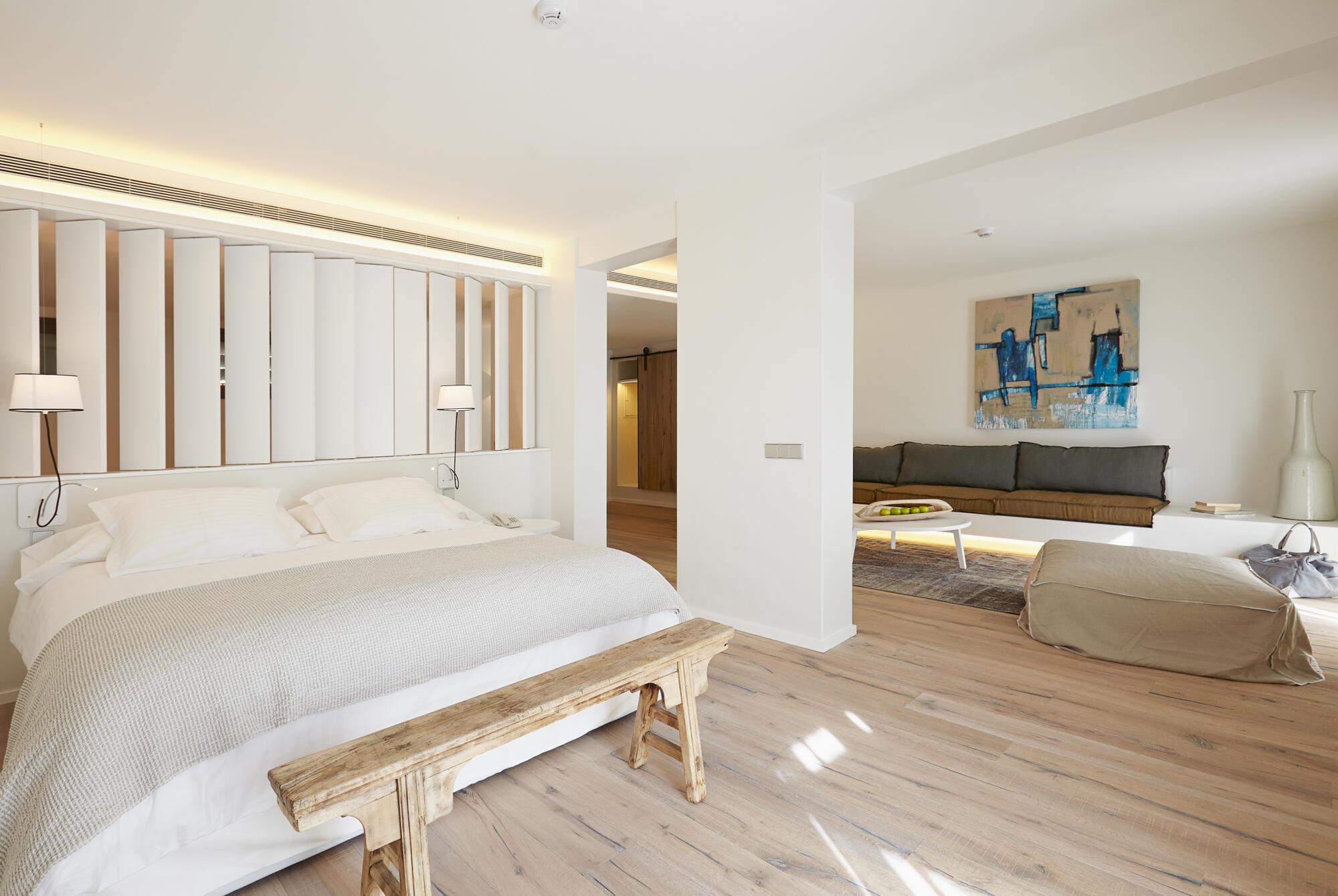 Photographie d'une chambre moderne et lumineuse avec lit double, canapé et tableau abstrait. Par Studio ZE, photographe d'intérieur à Toulouse.