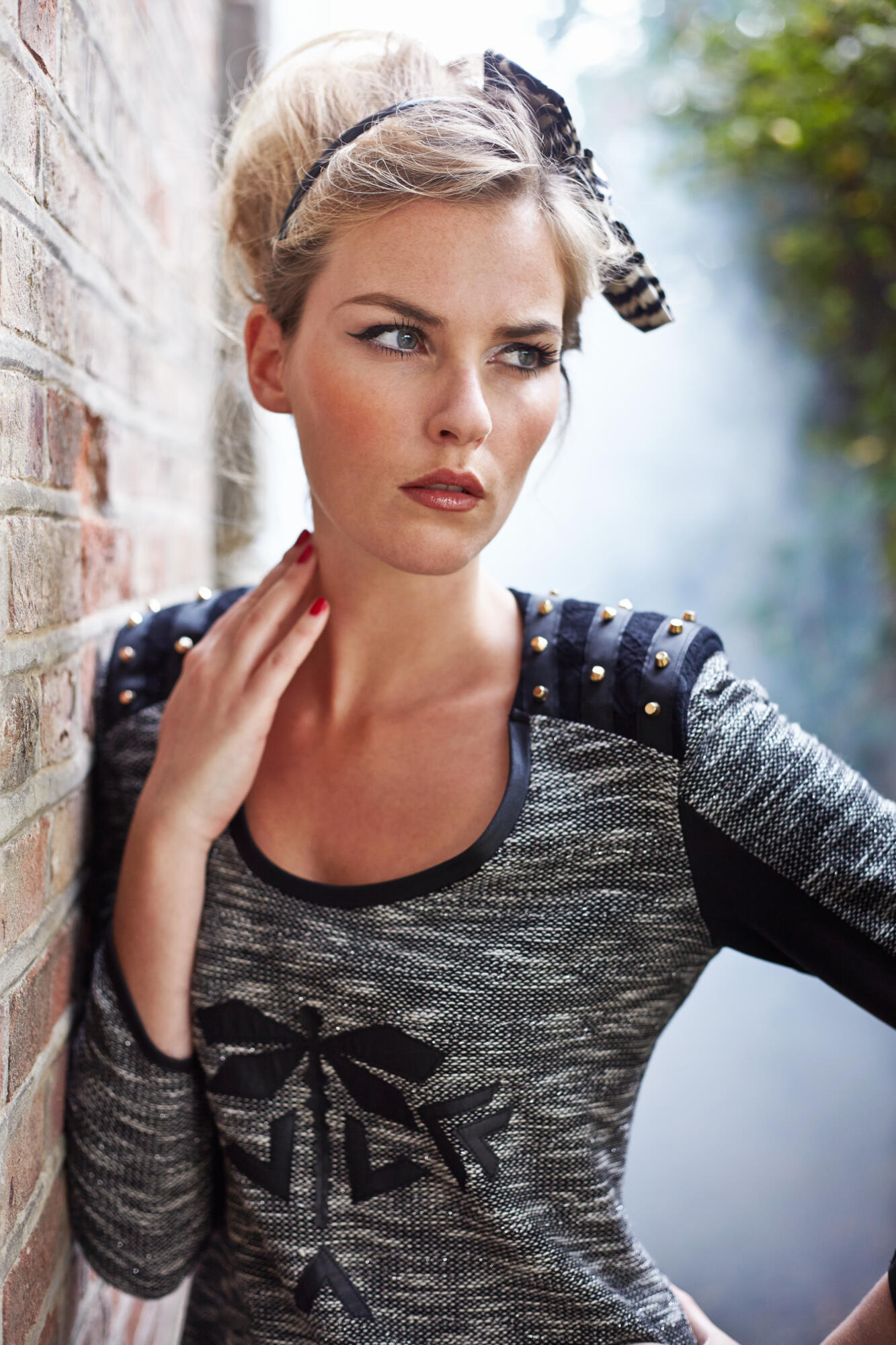 Photographie d'une femme blonde au regard intense, posant avec un haut à épaulettes cloutées et un bandeau fantaisie. Par Studio ZE, photographe mode à Toulouse.