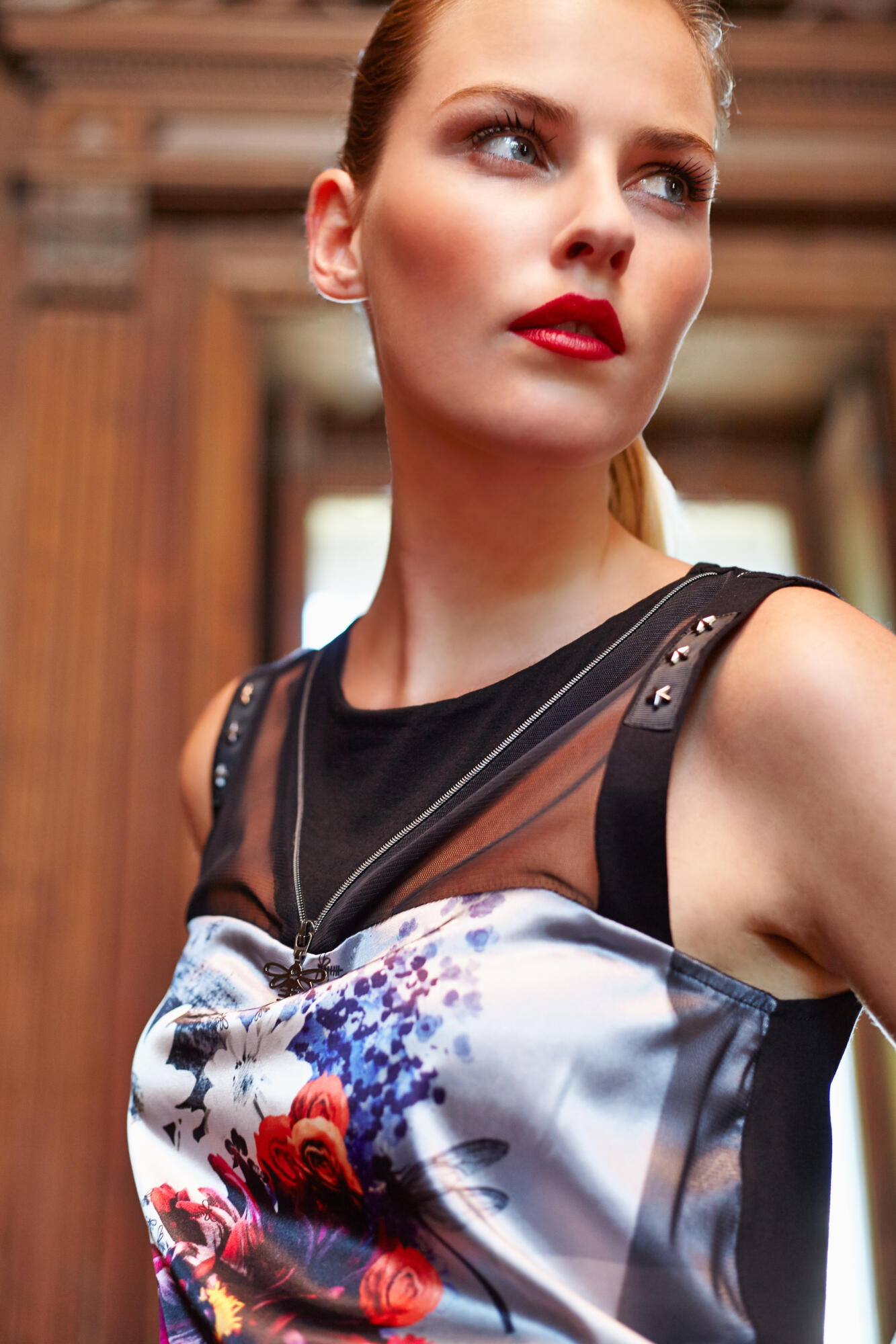 Photographie en gros plan d'une femme blonde aux lèvres rouges, vêtue d'un haut noir transparent avec un collier et des détails cloutés. Par Studio ZE, photographe mode à Toulouse.