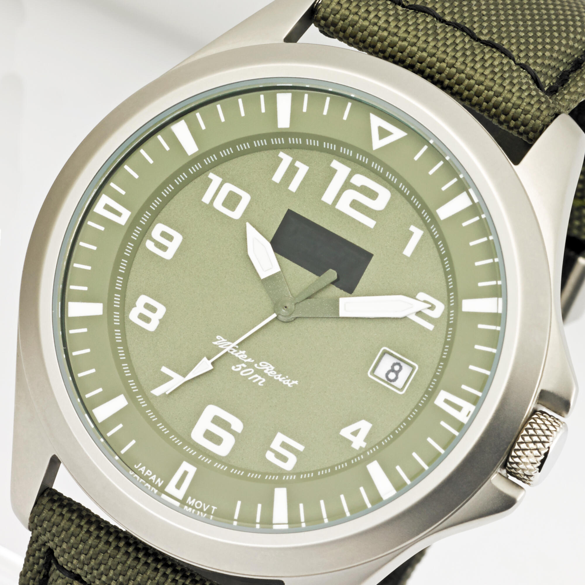 Photographie détaillée d'une montre homme cadran vert, bracelet en tissu kaki, idéale pour style casual. Par Studio ZE, photographe bijoux à Toulouse.