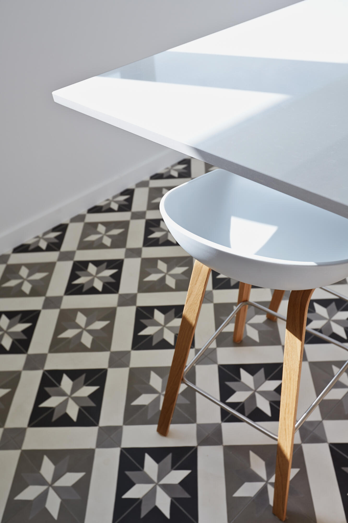 Photographie de carrelage à motif étoilé noir et blanc, avec tabouret de bar blanc, pour design intérieur. Par Studio ZE, photographe d'intérieur à Toulouse.