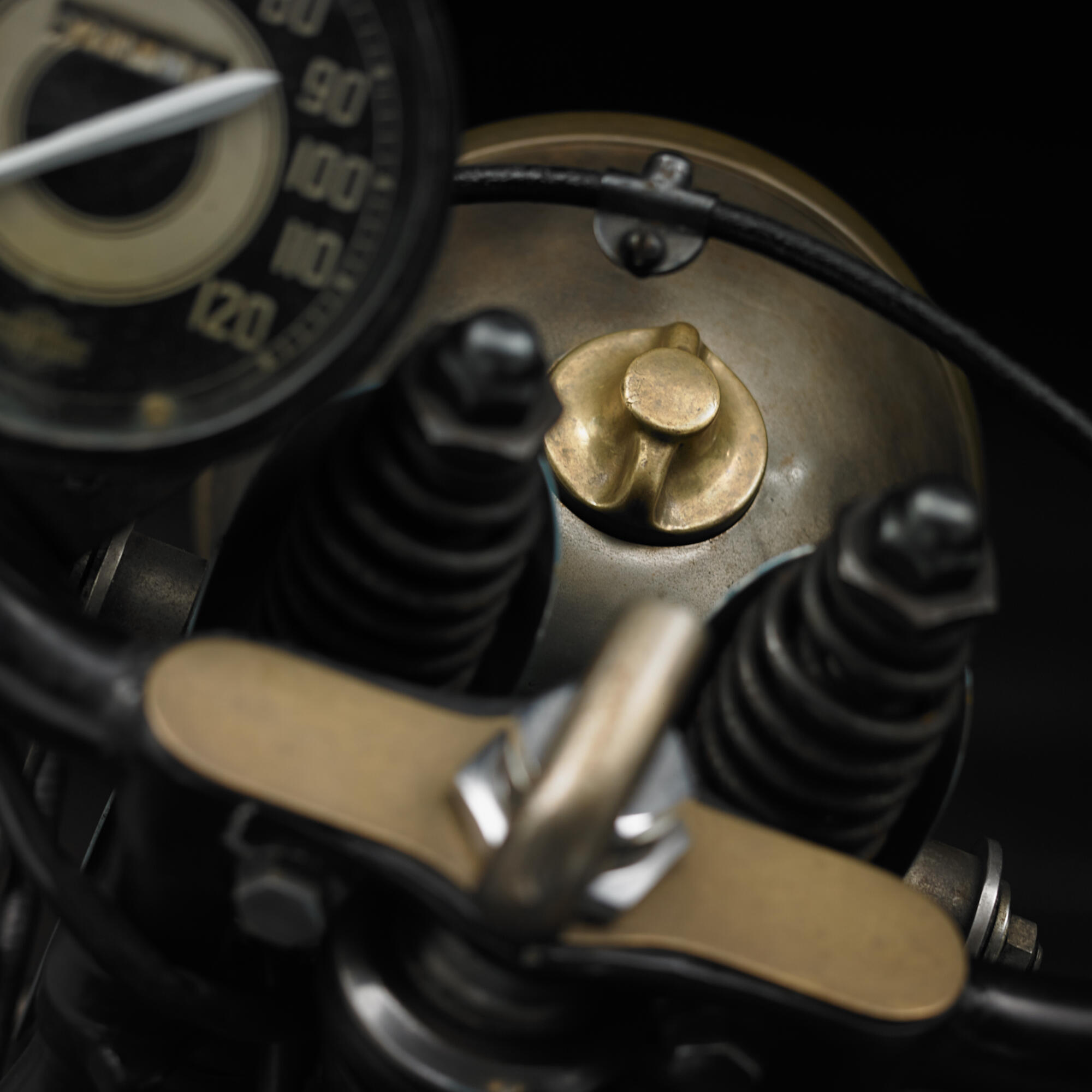 Photographie en gros plan d'un guidon et d'un tableau de bord de moto ancienne, avec des détails en laiton et des ressorts apparents. Par Studio ZE, photographe auto moto à Toulouse.