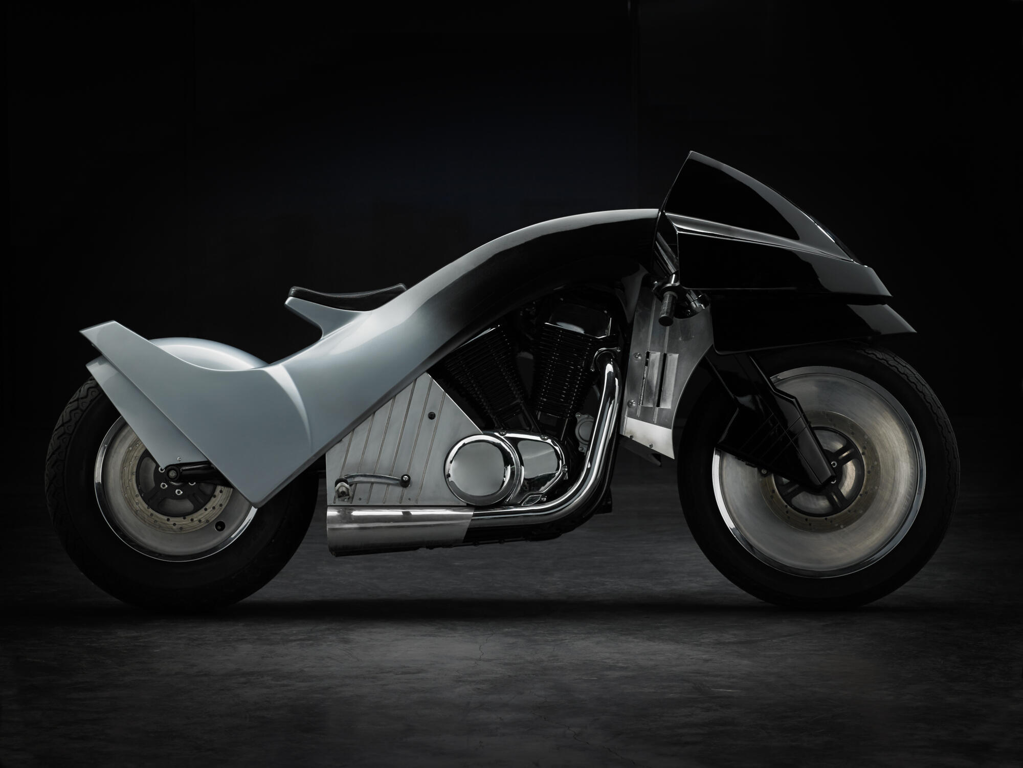 Photographie d'une moto customisée au design futuriste, noire et grise, avec des lignes épurées et des roues pleines. Par Studio ZE, photographe auto moto à Toulouse.