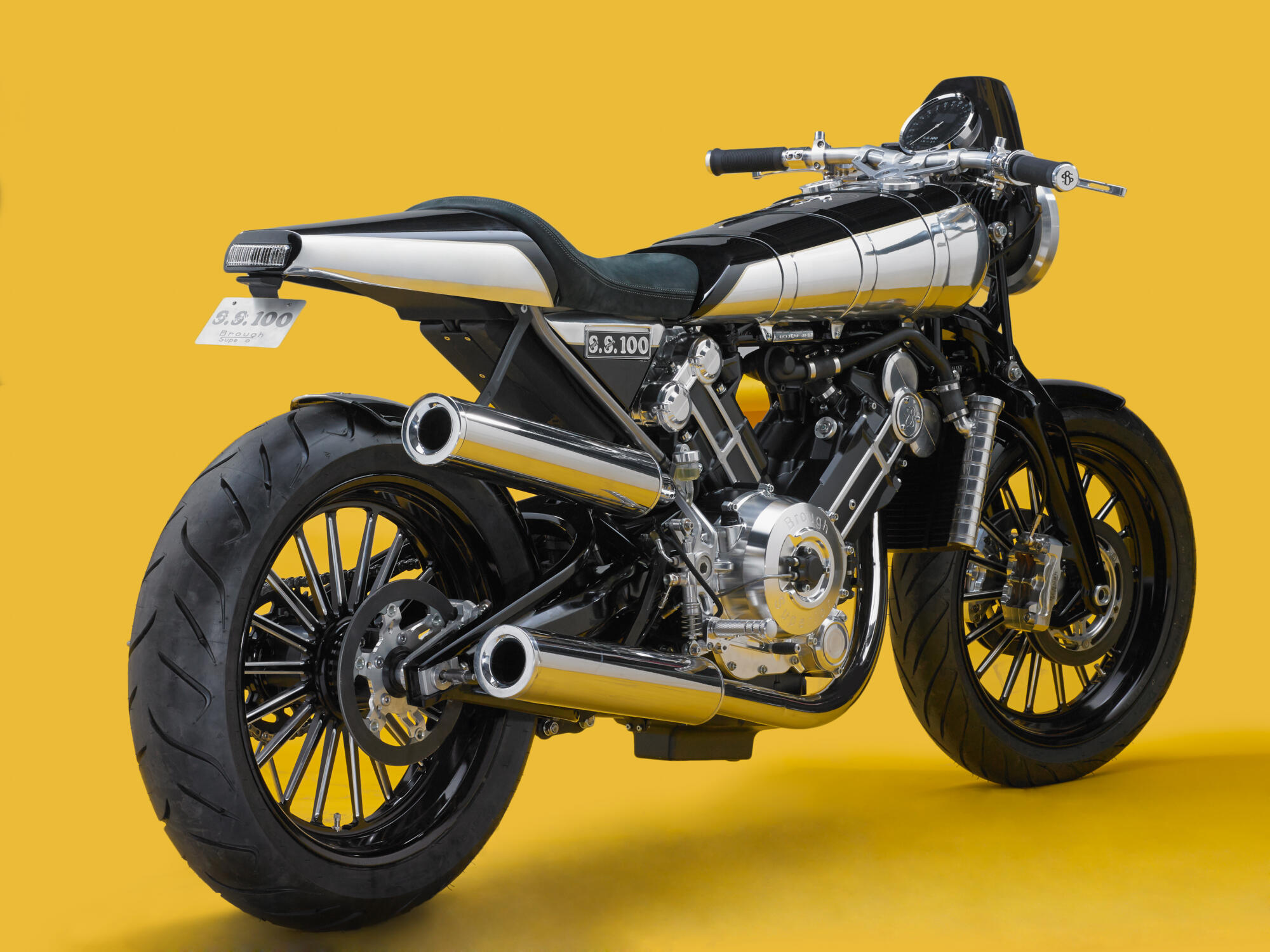 Photographie d'une moto noire et argentée au design classique, avec des échappements chromés et des roues à rayons, sur fond jaune. Par Studio ZE, photographe auto moto à Toulouse.