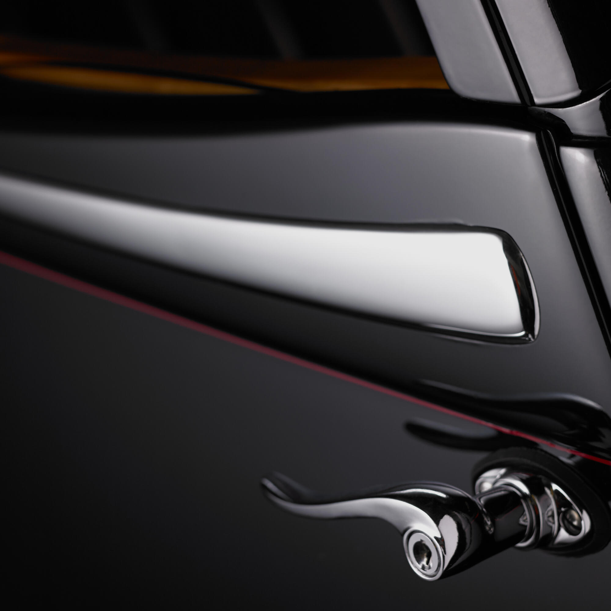 Photographie en gros plan d'une poignée de porte chromée et d'une serrure d'une voiture ancienne noire, avec une fine ligne rouge. Par Studio ZE, photographe auto moto à Toulouse.