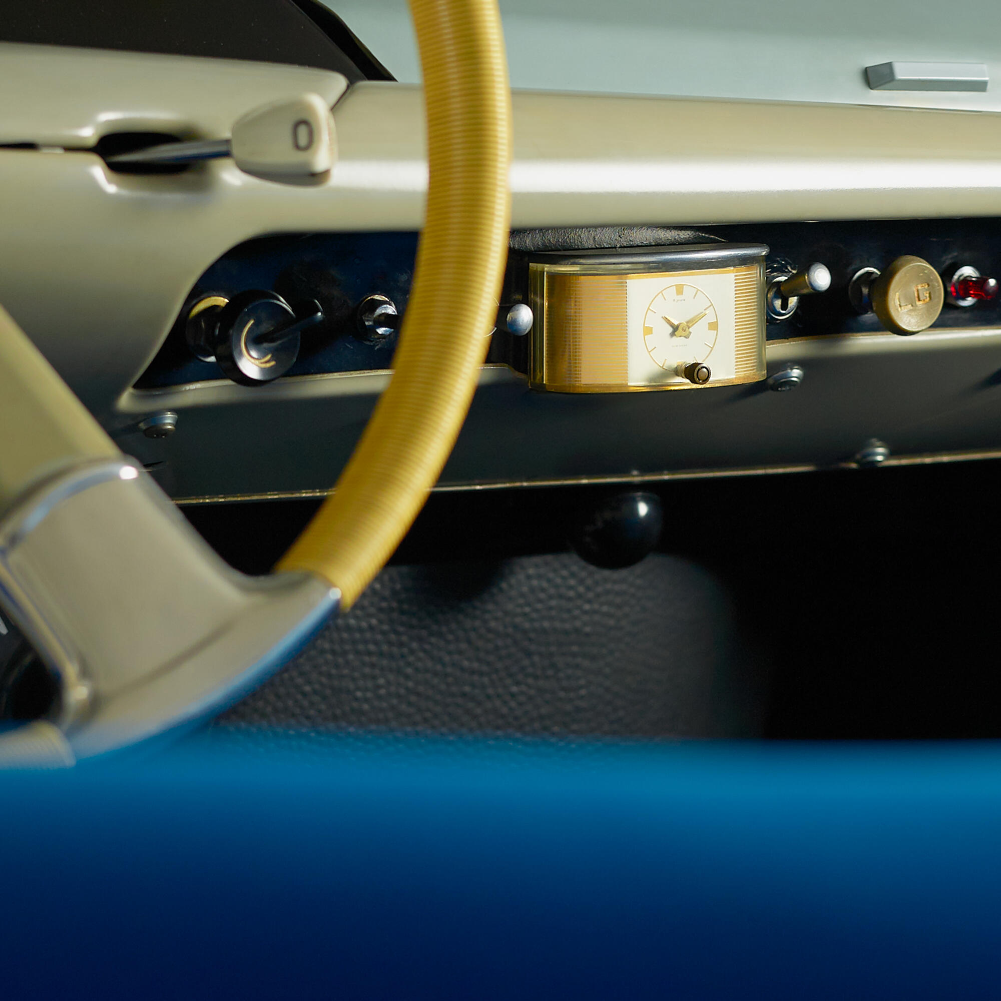 Photographie en gros plan du tableau de bord et du volant jaune d'une voiture ancienne, avec une horloge dorée intégrée. Par Studio ZE, photographe auto moto à Toulouse.