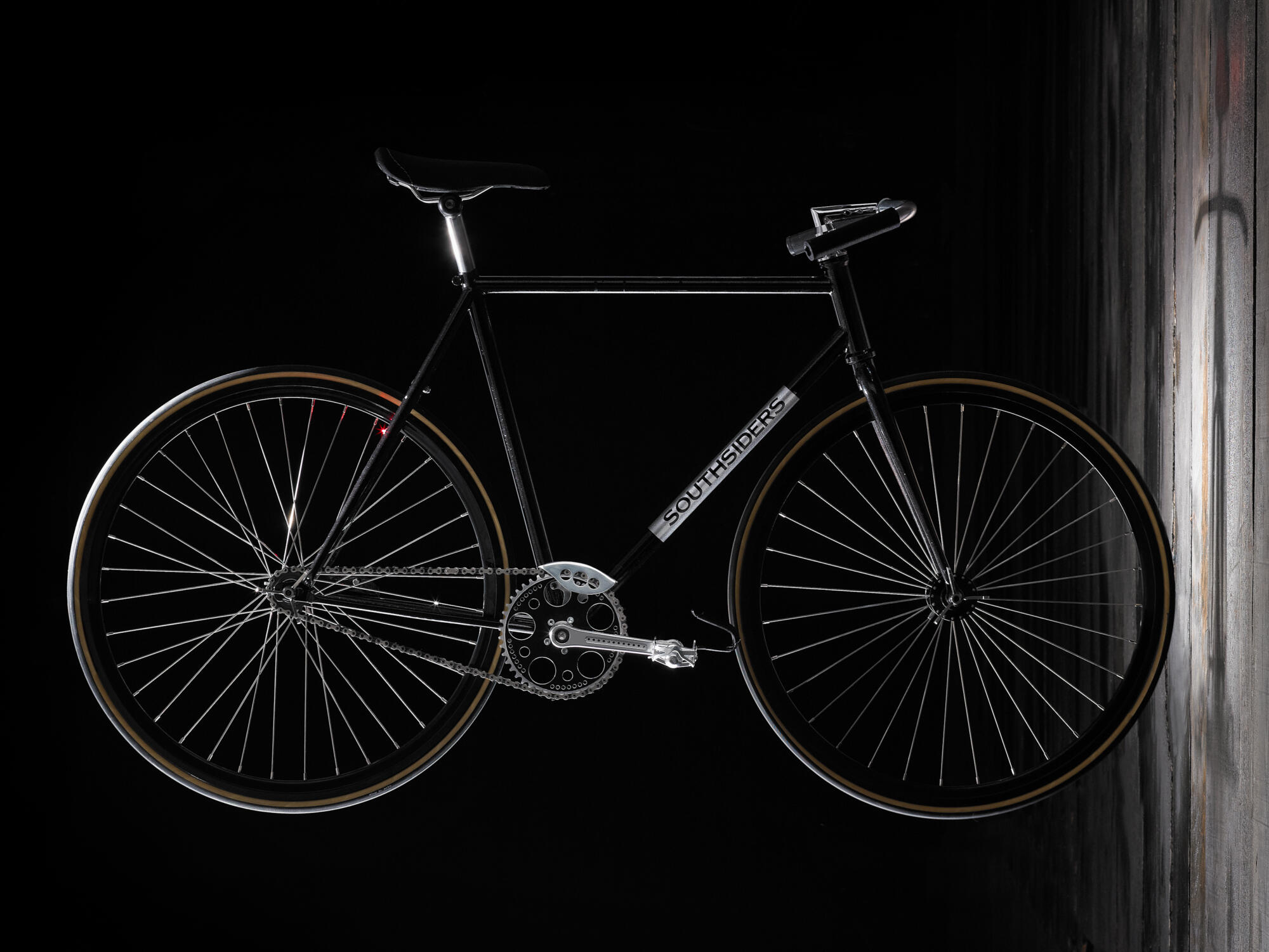 Photographie d'un vélo noir au design épuré, avec des roues à rayons et le nom 'SOUTHSIDERS' sur le cadre, sur fond sombre. Par Studio ZE, photographe auto moto à Toulouse.