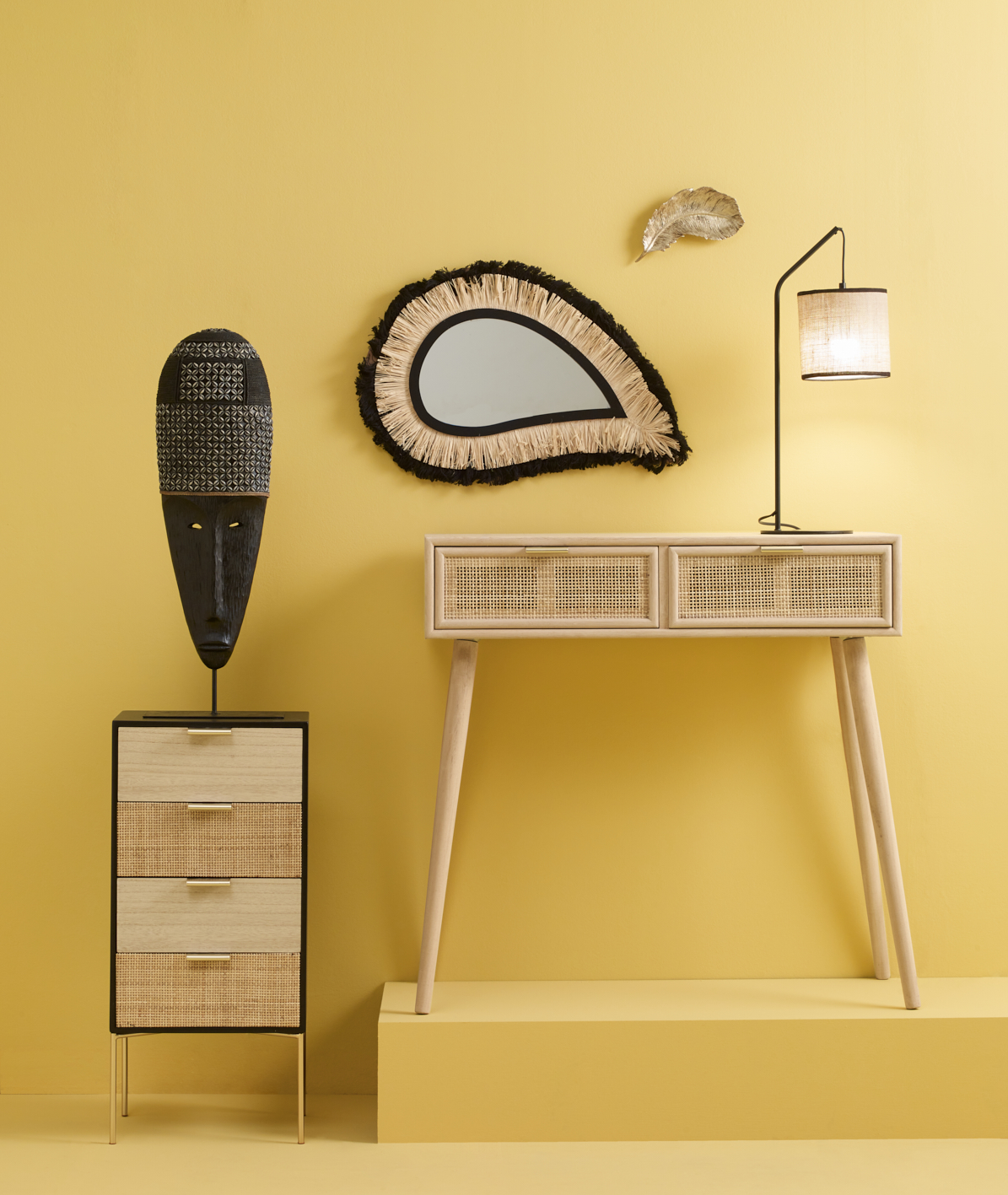 Photographie d'une console en rotin et bois clair, meuble à tiroirs et masque tribal sur mur jaune vif. Par Studio ZE, photographe d'intérieur à Toulouse.