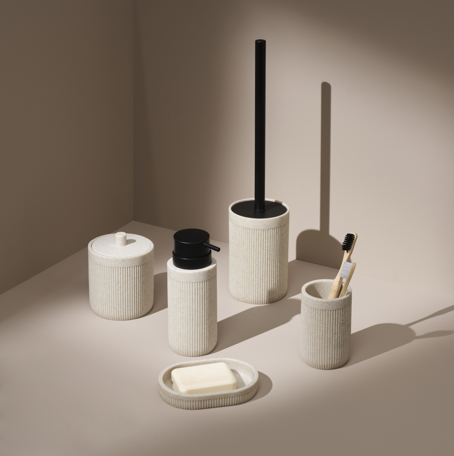 Photographie professionnelle d'un set d'accessoires de salle de bain texturés (distributeur, gobelet, pot, porte-balai) avec savon. Image réalisée par Studio ZE, photographe d'objet et de décoration intérieure à Toulouse.