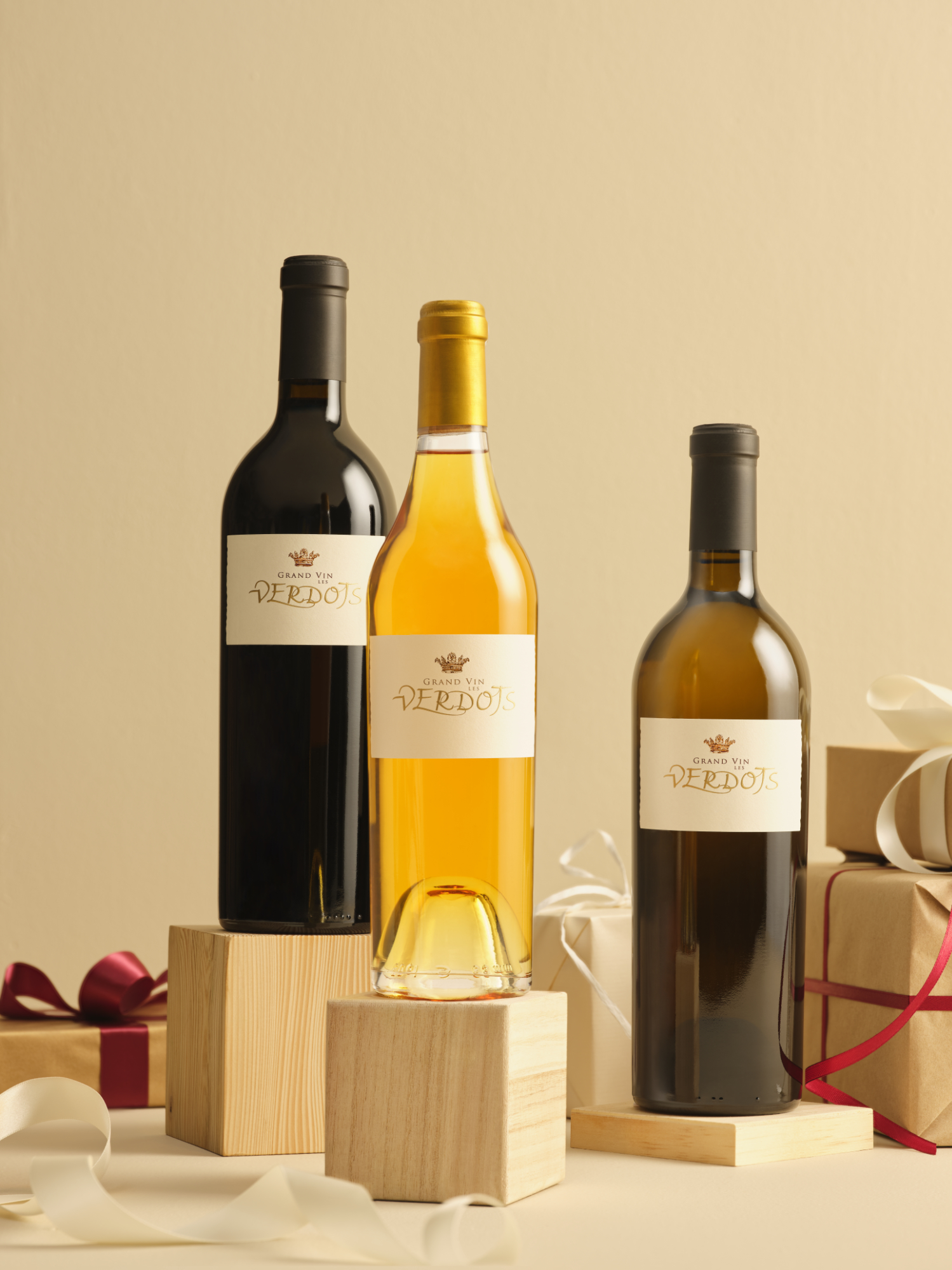 Photographie de trois bouteilles de vin Grand Vin VERDOTS (rouge, blanc) sur blocs en bois, avec cadeaux. Par Studio ZE, photographe de vin à Toulouse.
