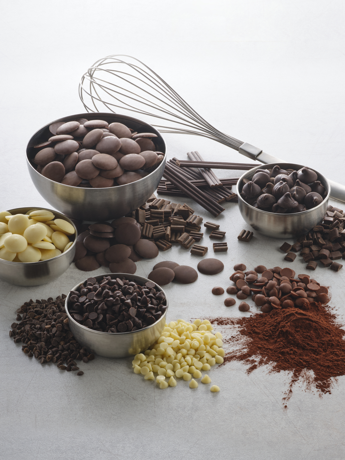Photographie de différents chocolats (pépites, disques, bâtons) et cacao en poudre pour pâtisserie. Par Studio ZE, photographe culinaire à Toulouse.