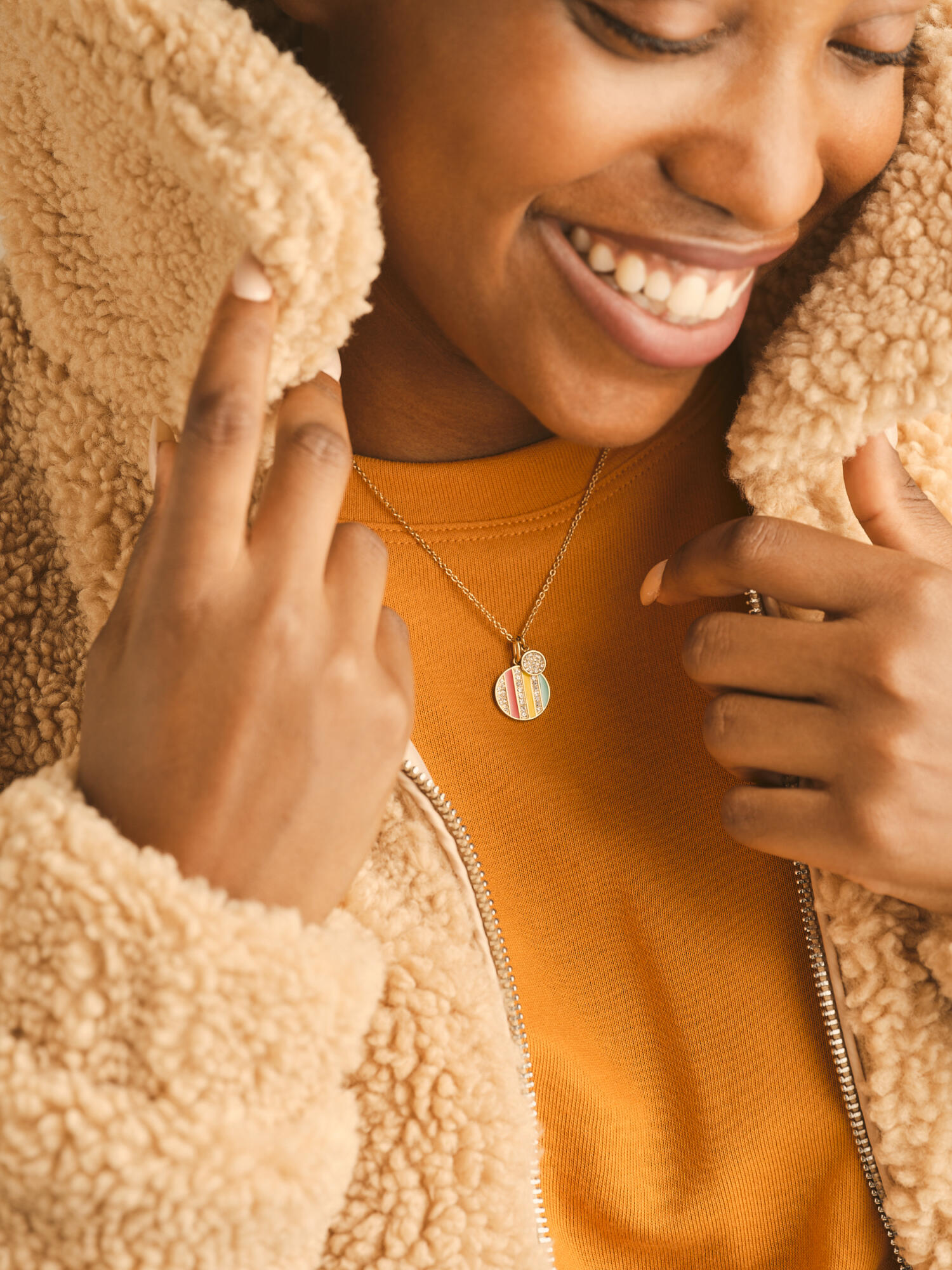 Photographie en gros plan d'une femme souriante, portant un collier coloré et une veste en sherpa. Par Studio ZE, photographe humain à Toulouse.