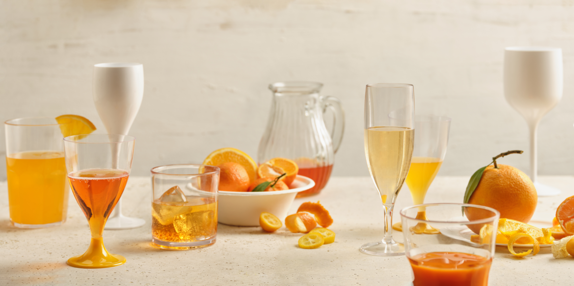 Photographie de divers verres (flûtes, gobelets) remplis de boissons colorées aux agrumes. Par Studio ZE, photographe de verres et boissons à Toulouse.