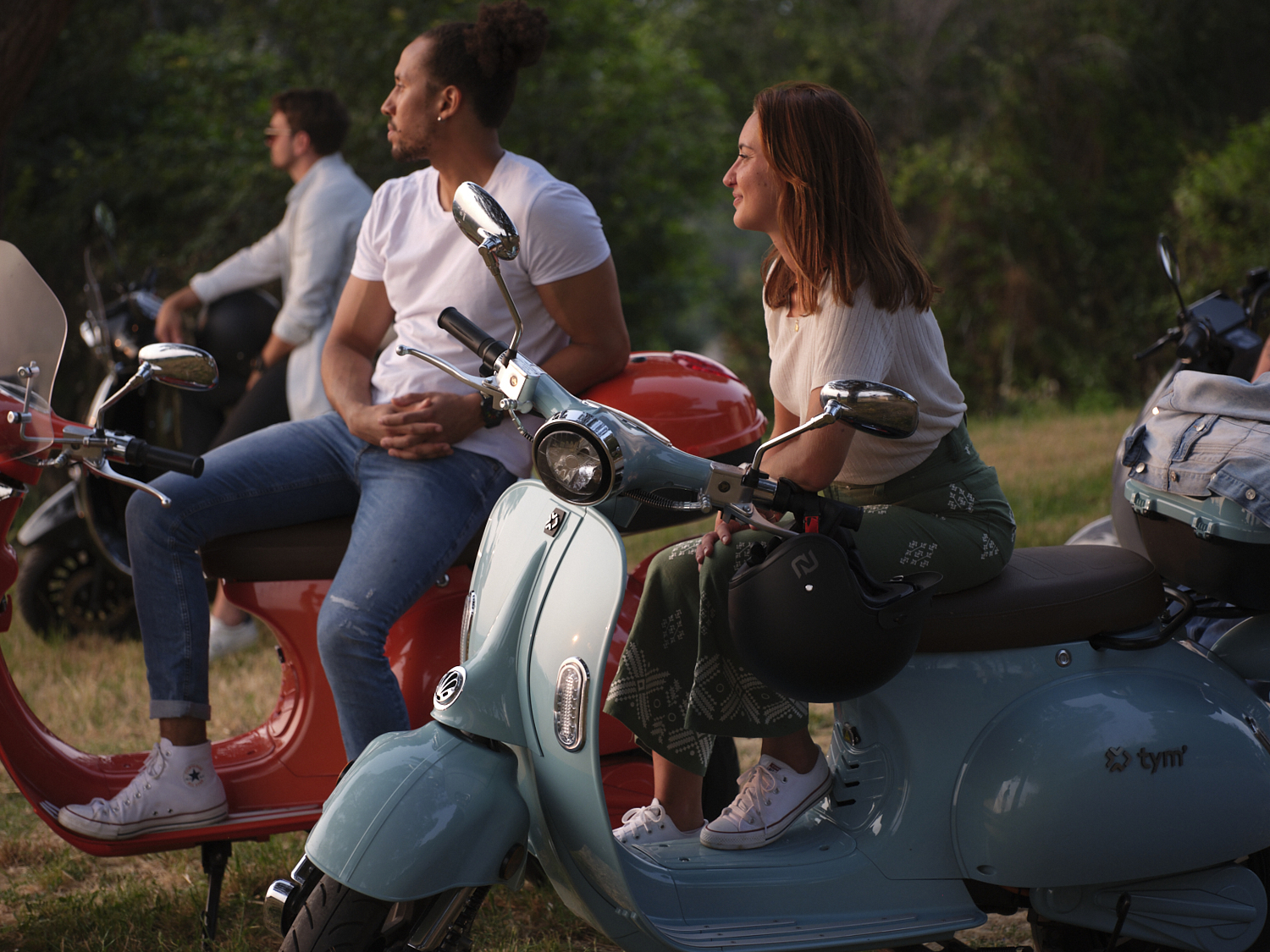 Photographie d'un groupe d'amis adultes assis sur des scooters colorés, profitant d'une balade au coucher du soleil. Par Studio ZE, photographe humain à Toulouse.